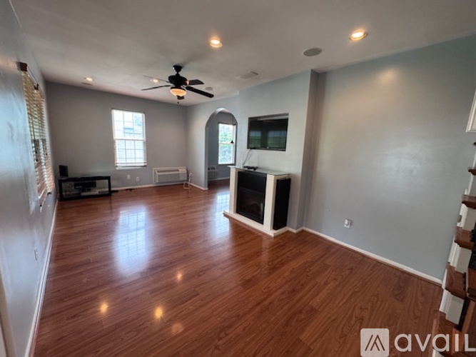 A spacious room with wood flooring and a ceiling fan.