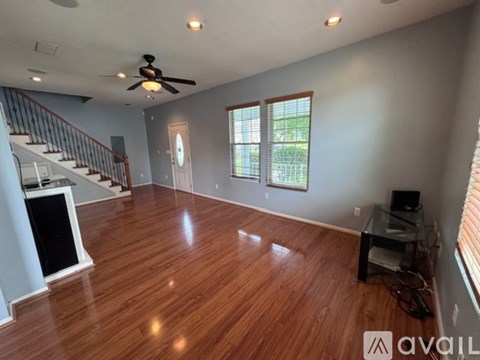 A spacious room with wood flooring and a ceiling fan.