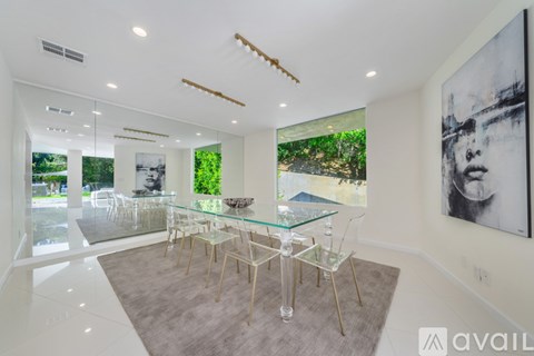 A modern dining room with a glass table and chairs.