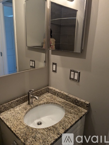 A bathroom sink with a granite countertop and a large mirror above it.
