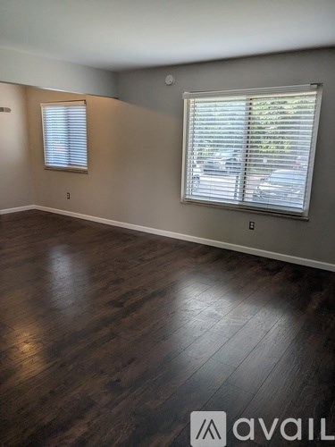 A room with wooden floors and a window with blinds.