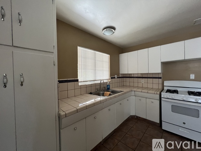 A kitchen with white cabinets and a white stove top oven.