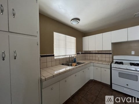A kitchen with white cabinets and a white stove top oven.