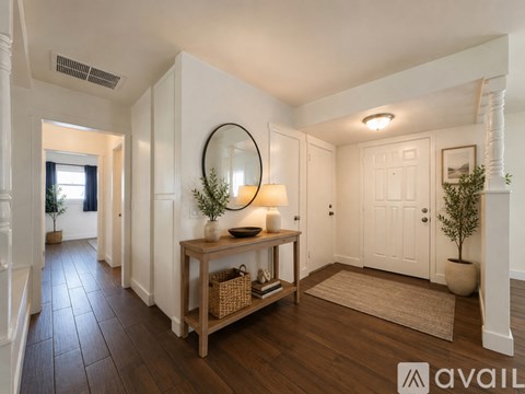 A hallway with a wooden table and a mirror.