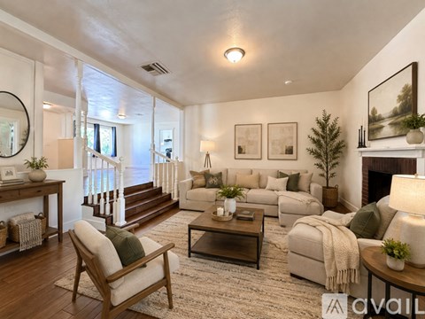 A living room with a white couch, a wooden chair, and a coffee table.