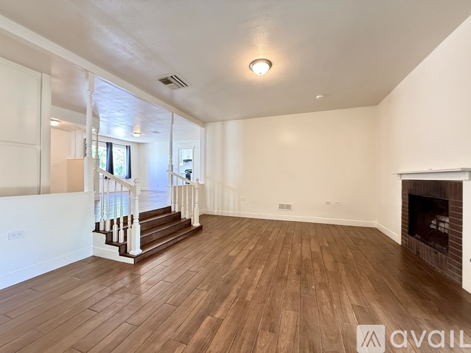 A spacious room with wooden flooring and a fireplace.