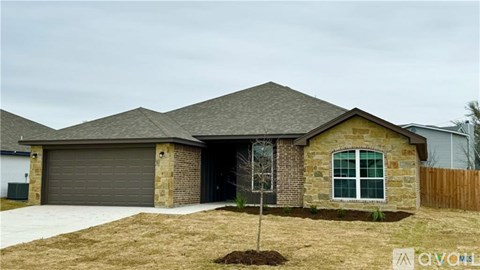 A house with a grey garage door and a tree in front.