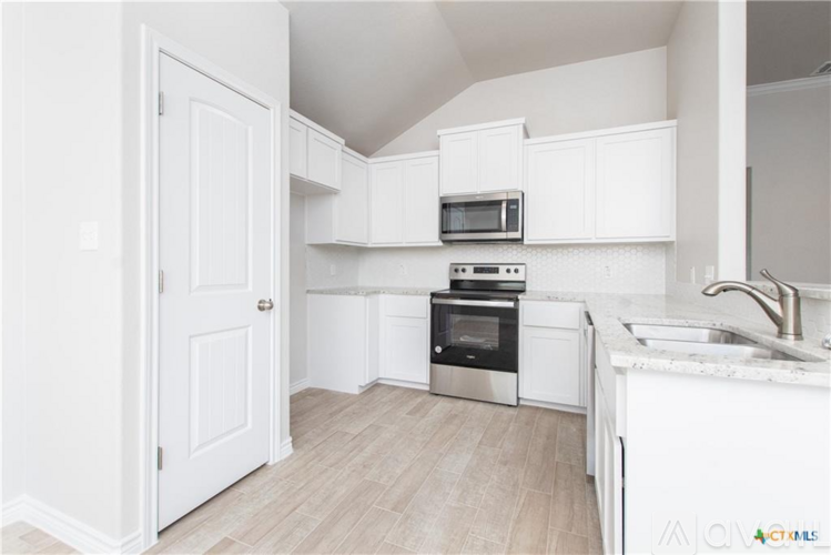A kitchen with white cabinets and a white sink.
