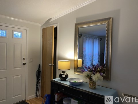 A lamp with a yellow shade sits on a desk next to a mirror.