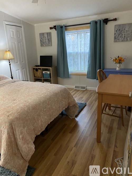 A bedroom with a bed, desk, and chair.