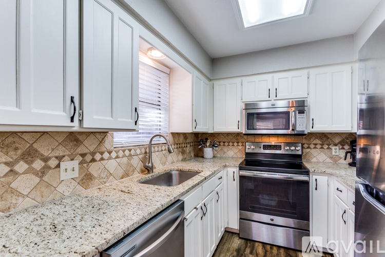 A kitchen with white cabinets and a granite countertop.