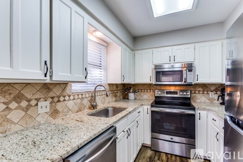 A kitchen with white cabinets and a granite countertop.