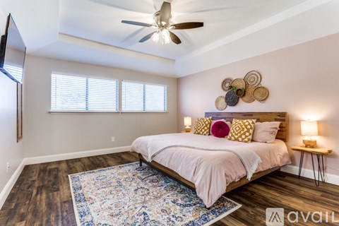 A bedroom with a bed, a ceiling fan, and a rug.