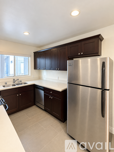 A kitchen with a stainless steel refrigerator and brown cabinets.