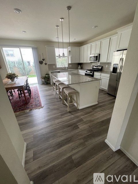 A kitchen with a dining table and chairs is visible.