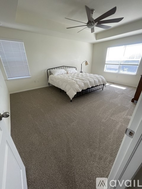 A bedroom with a bed, carpet, and a ceiling fan.