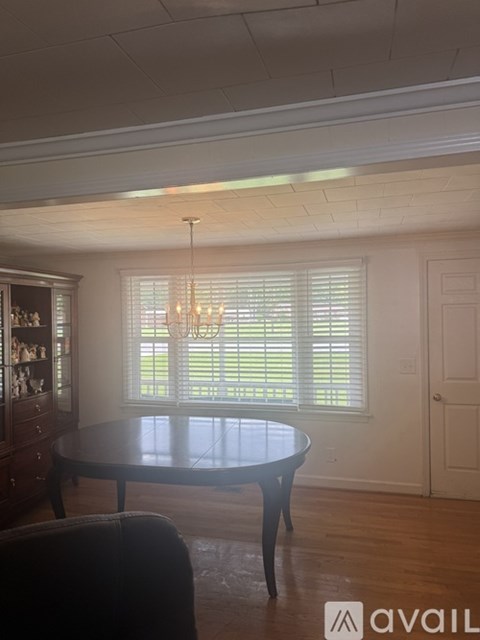 A dining room with a round table and a chandelier.