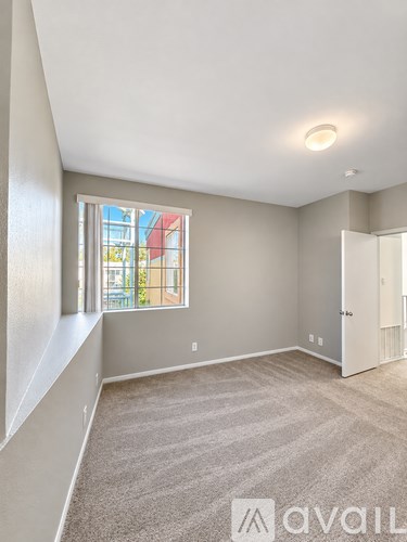 A room with a carpeted floor and a window with a view of a building outside.