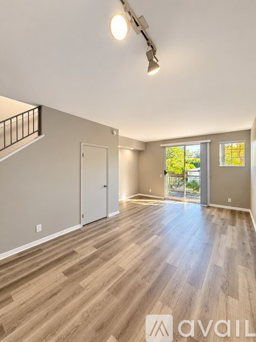 A spacious room with wooden flooring and a balcony with a railing.
