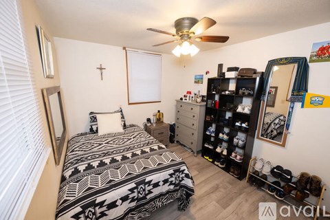 A bedroom with a bed, dresser, and a ceiling fan.