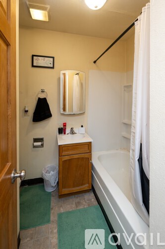 A bathroom with a tub, sink and mirror.