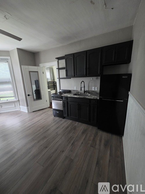 A kitchen with black cabinets and a wooden floor.