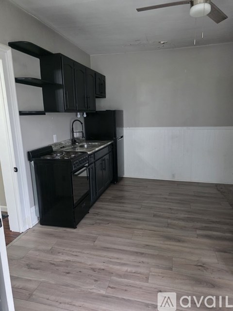 A kitchen with black cabinets and a wooden floor.