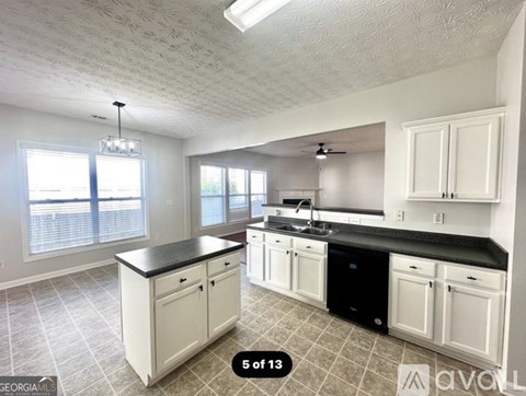 A kitchen with white cabinets and black countertops.