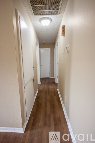 A long hallway with wood floors and white walls.