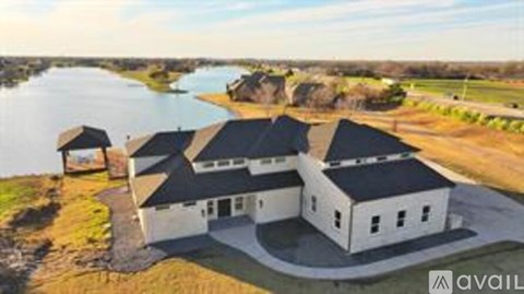A white house with a black roof is situated near a body of water.