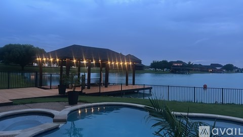 A pool area with a hot tub and a building with lights on.