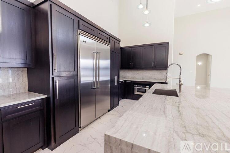 A kitchen with dark wood cabinets and a marble countertop.