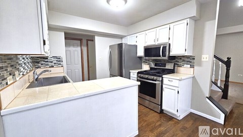 A kitchen with white cabinets and a black fridge.