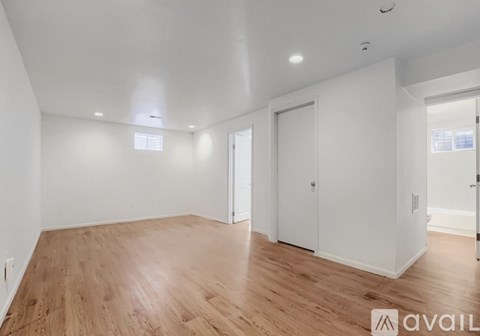 A spacious room with wooden flooring and white walls.