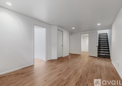 A spacious room with wooden flooring and white walls.