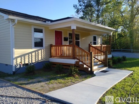 A small house with a red door and a wooden porch.