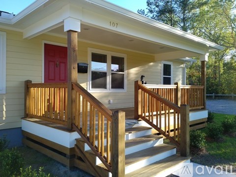 A small house with a red door and wooden railings.
