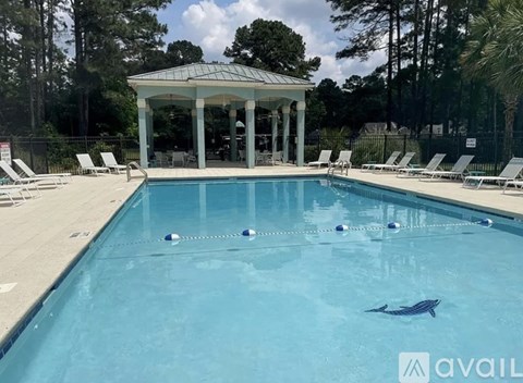 A pool with a gazebo and a dolphin float in the middle.