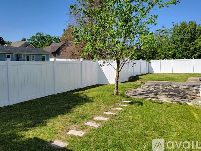 A white fence with a tree in the middle of a grassy area.