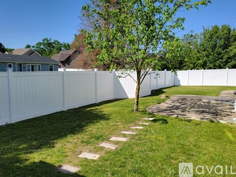 A white fence with a tree in the middle of a grassy area.