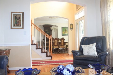A living room with a black leather chair and a wooden staircase.
