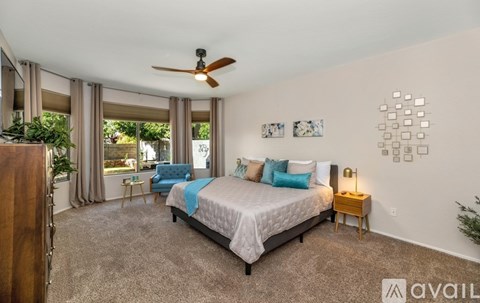 A bedroom with a bed, a ceiling fan, and a window with curtains.
