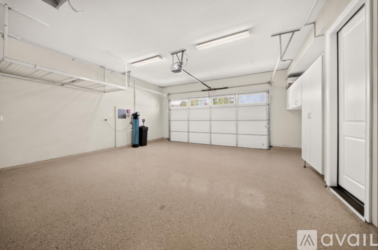A spacious room with a carpeted floor, white walls, and a white door on the right side.