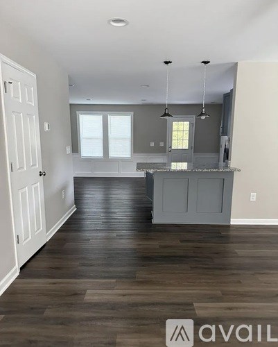 A kitchen with a dark wood floor and white walls.