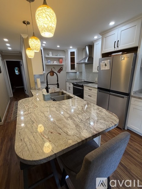 A kitchen with a marble table and pendant lights.