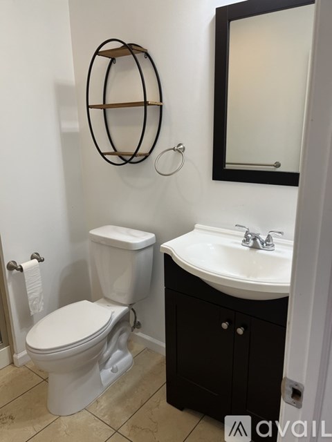 A bathroom with a toilet, sink and mirror.