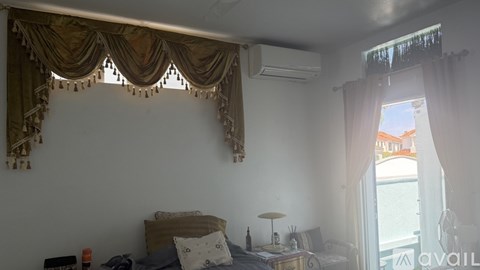 A bedroom with a bed, nightstand, and window with curtains.