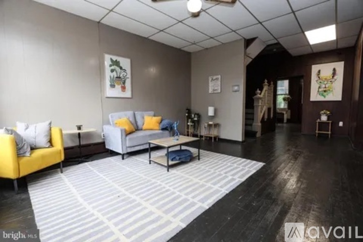 A living room with a yellow couch and a grey rug.