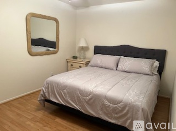 A bedroom with a bed, nightstand, and mirror.
