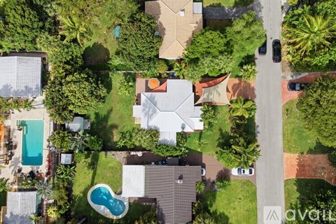 A bird's eye view of a residential area with houses, a pool, and a street.